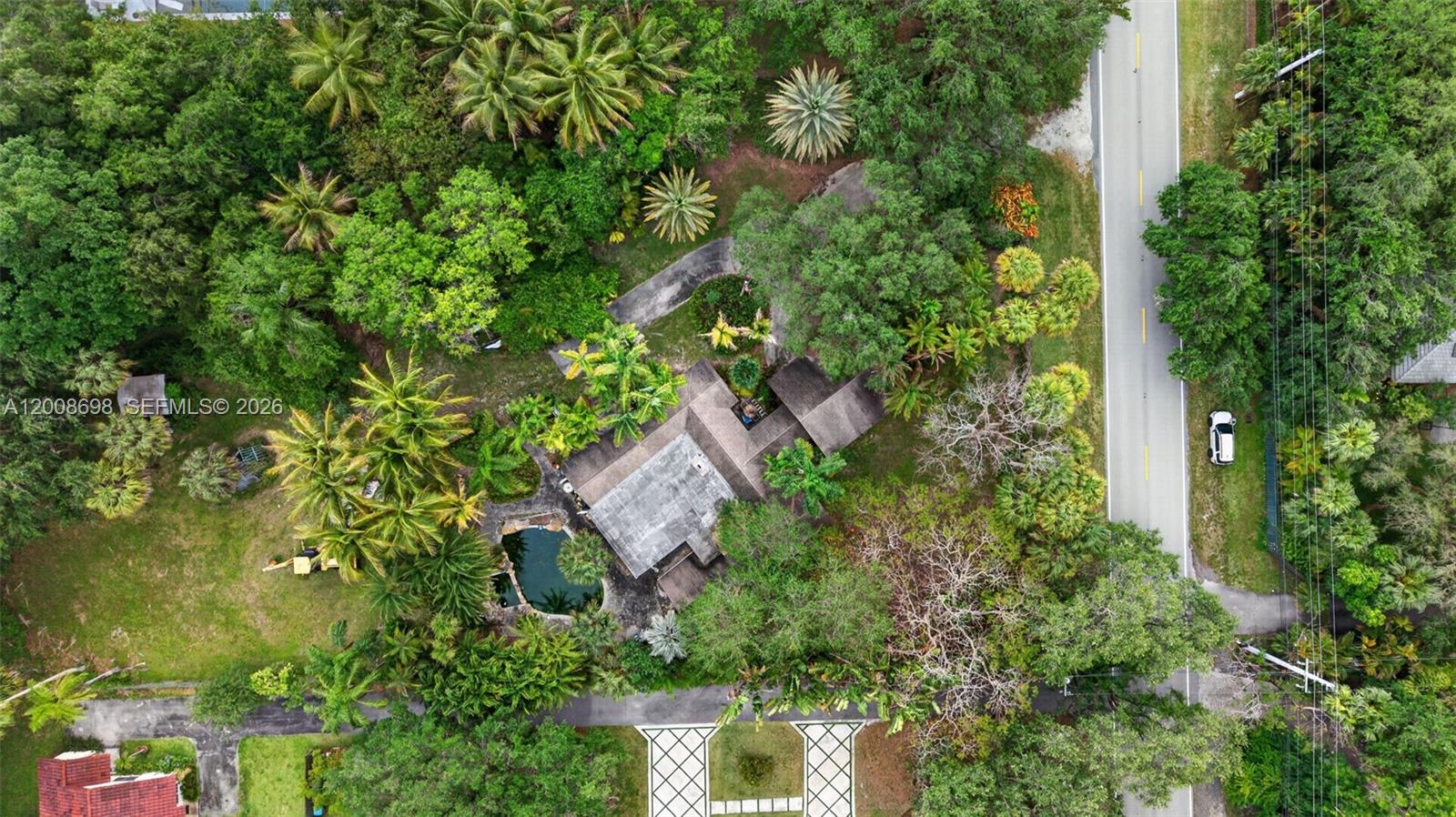 An aerial view shows a house with a pool surrounded by dense tropical vegetation — 8339 SW 112th St, Miami FL 33156, MIAMI, FL