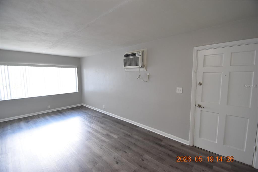 An empty room features gray walls, wood-look flooring, a window, and a wall-mounted air conditioner — 302 DANUBE AVENUE UNIT 5, TAMPA, FL
