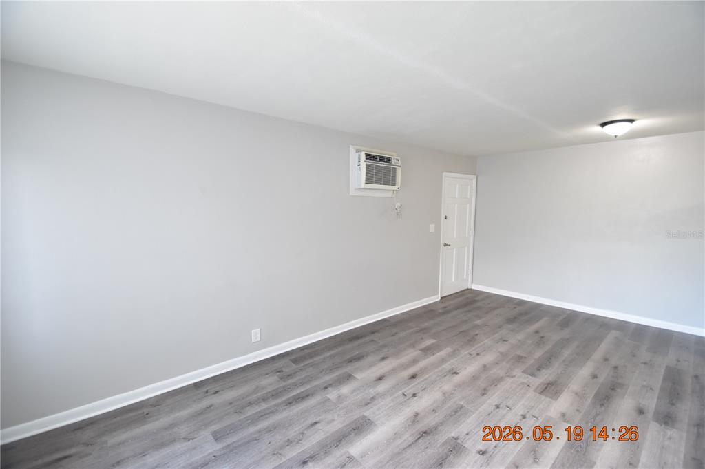 An empty room features light gray walls, wood-look flooring, and a wall-mounted air conditioner — 302 DANUBE AVENUE UNIT 5, TAMPA, FL