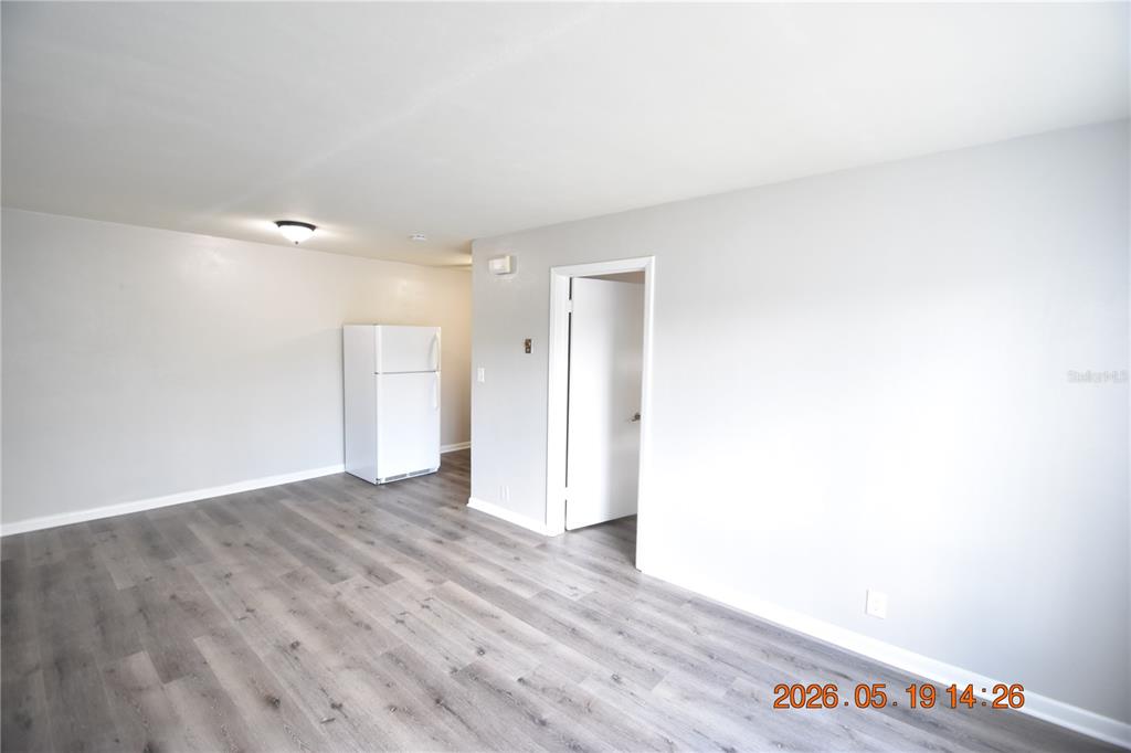 A room with gray wood-look flooring, light gray walls, and a white refrigerator — 302 DANUBE AVENUE UNIT 5, TAMPA, FL