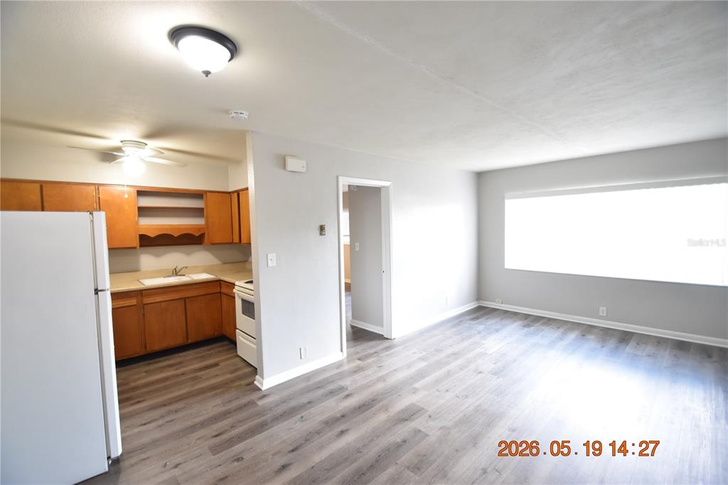 An open-concept living area features gray wood-look flooring and an adjacent kitchen with wooden cabinets — 302 DANUBE AVENUE UNIT 5, TAMPA, FL