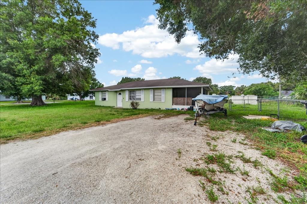 A light green single-story house with a gravel driveway and a boat on a trailer — 2213 NW 3RD STREET, OKEECHOBEE, FL