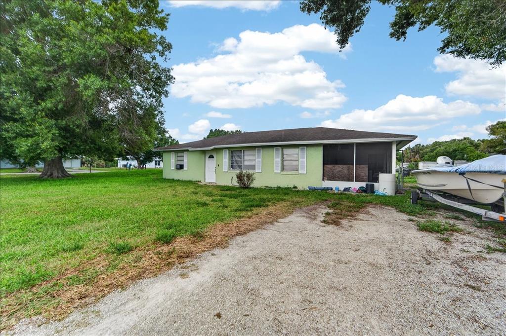 A light green, single-story house with a screened-in porch and a boat on a trailer — 2213 NW 3RD STREET, OKEECHOBEE, FL