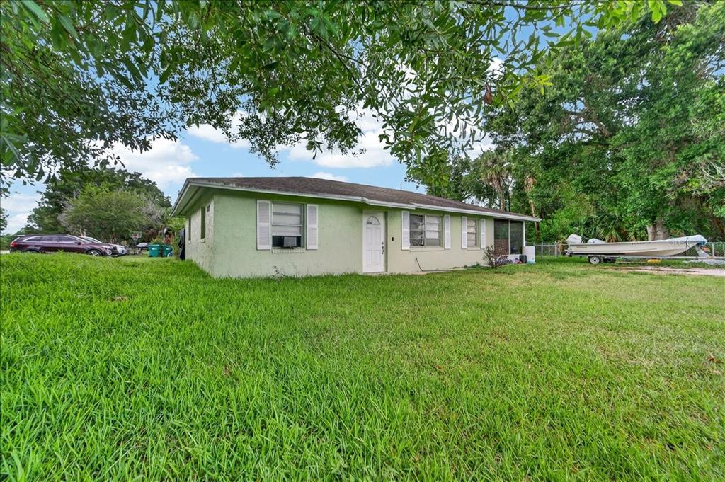 A light green, single-story house with a white door and shutters sits on a grassy lot — 2213 NW 3RD STREET, OKEECHOBEE, FL