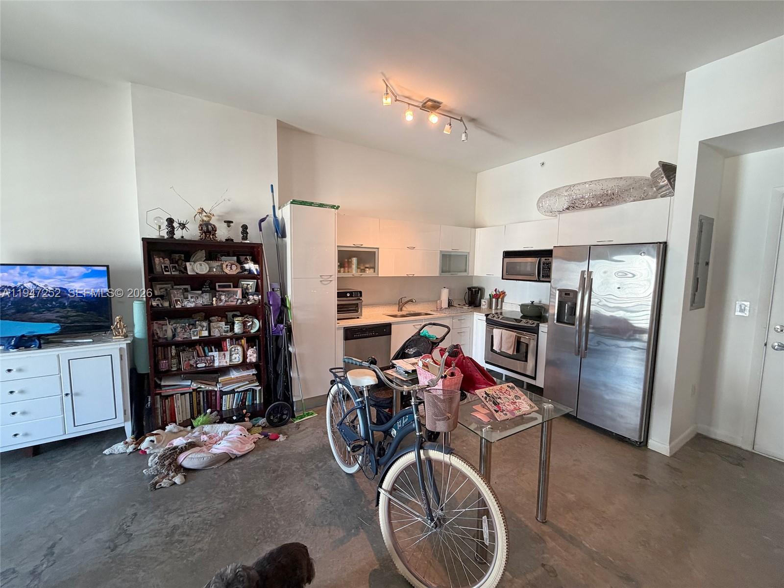 A kitchen with stainless steel appliances, white cabinets, and a bicycle parked in the center — 133 NE 2nd Ave # 2107, Miami FL 33132, MIAMI, FL