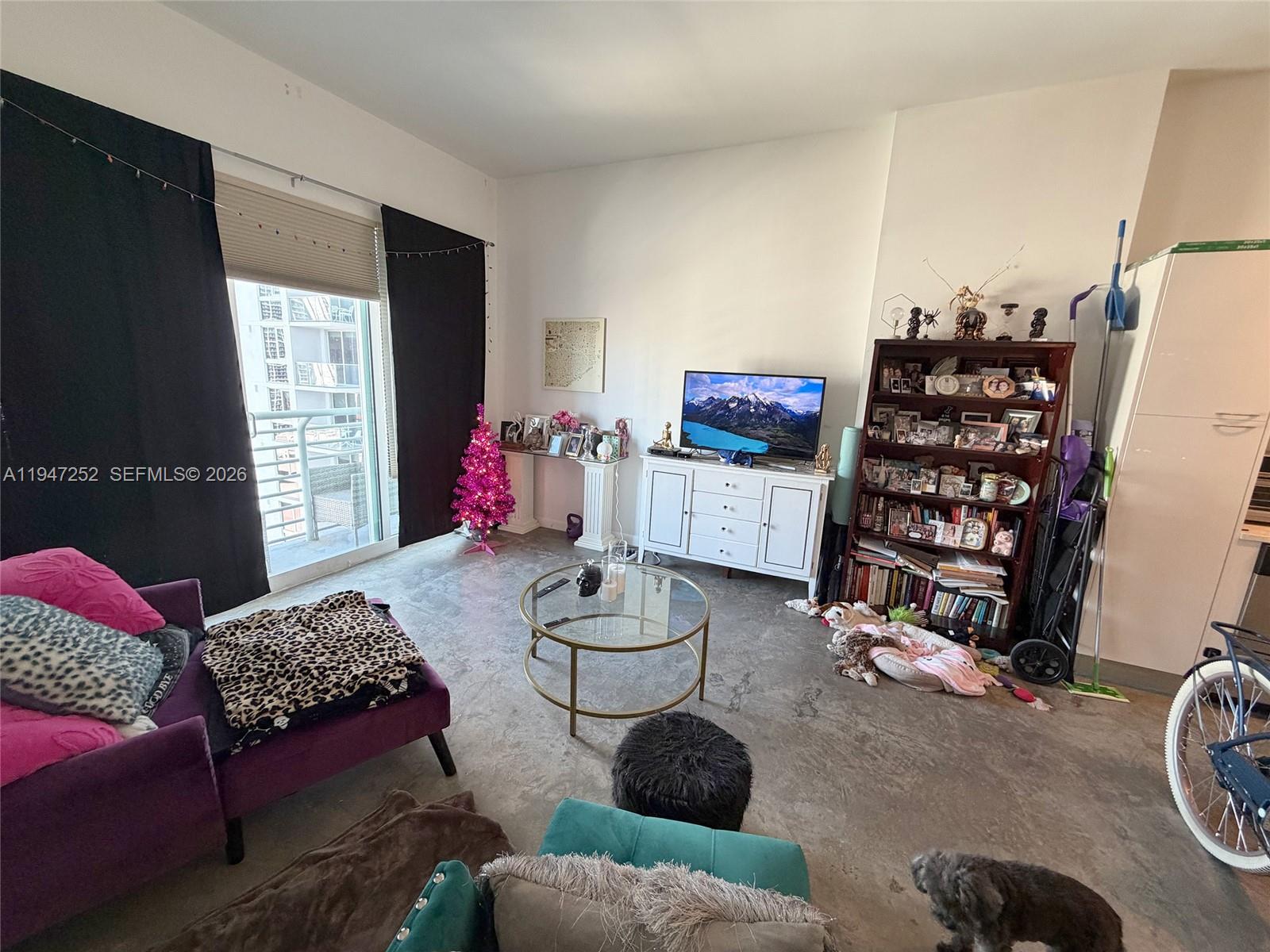 A living room features a purple sofa, a glass coffee table, and a tall bookshelf — 133 NE 2nd Ave # 2107, Miami FL 33132, MIAMI, FL