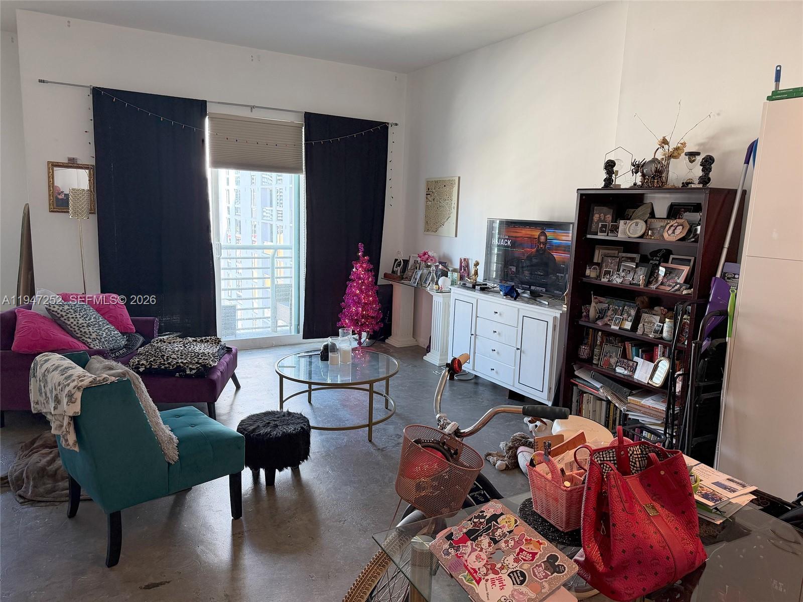 A living room features a purple sofa, teal armchair, glass coffee table, and a bookshelf — 133 NE 2nd Ave # 2107, Miami FL 33132, MIAMI, FL
