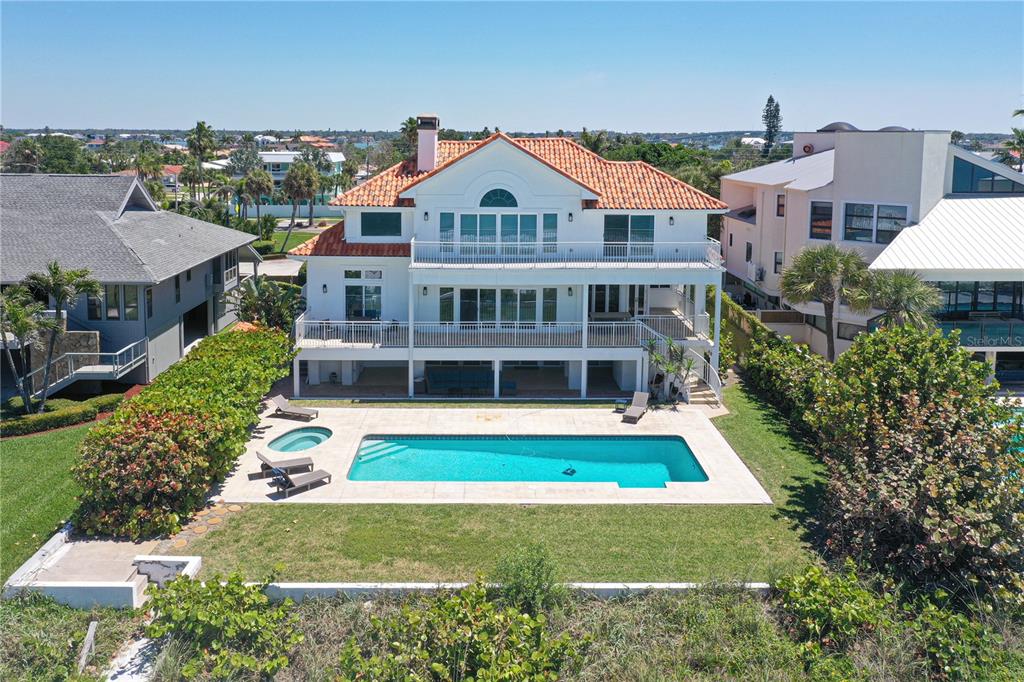 A multi-story white house with a tile roof, pool, and spa overlooking a coastal area — 1800 GULF BOULEVARD, BELLEAIR BEACH, FL
