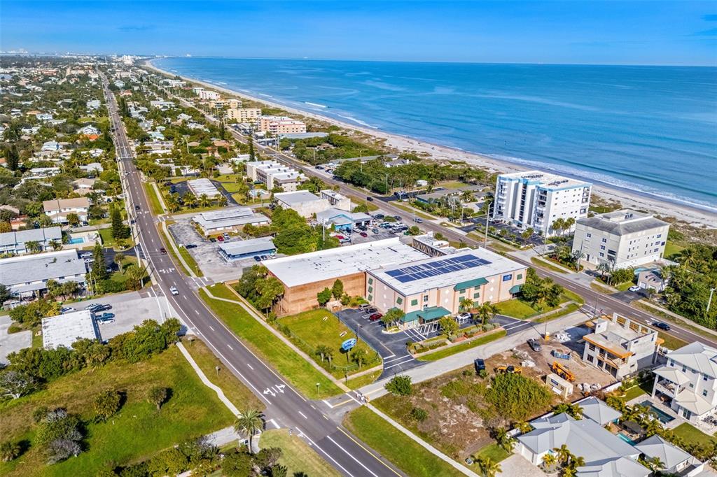 An aerial view shows a coastal road, commercial buildings, and residential properties near the ocean — 1900 S. ATLANTIC AVENUE, COCOA BEACH, FL
