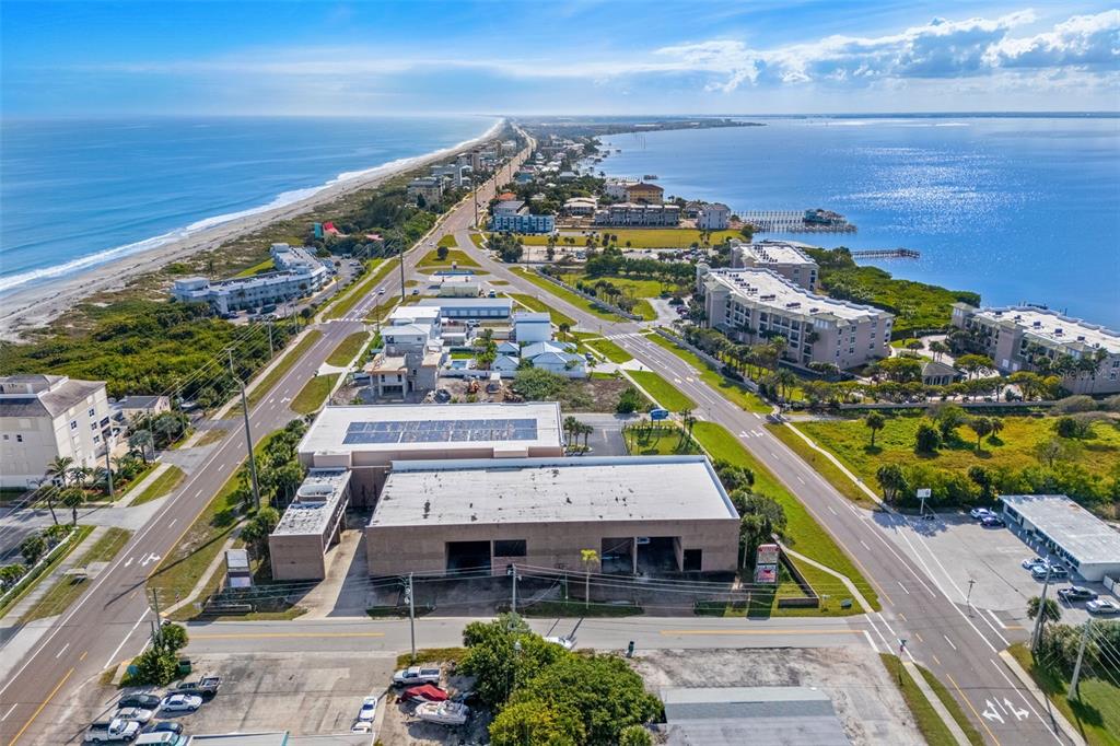 An aerial view shows a commercial building situated between a coastal road and the ocean — 1900 S. ATLANTIC AVENUE, COCOA BEACH, FL