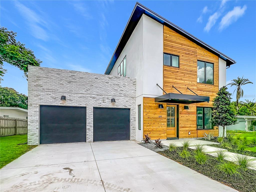 A modern two-story house features a white stucco exterior, wood siding, and a two-car garage — 1205 FALCON DRIVE, ORLANDO, FL