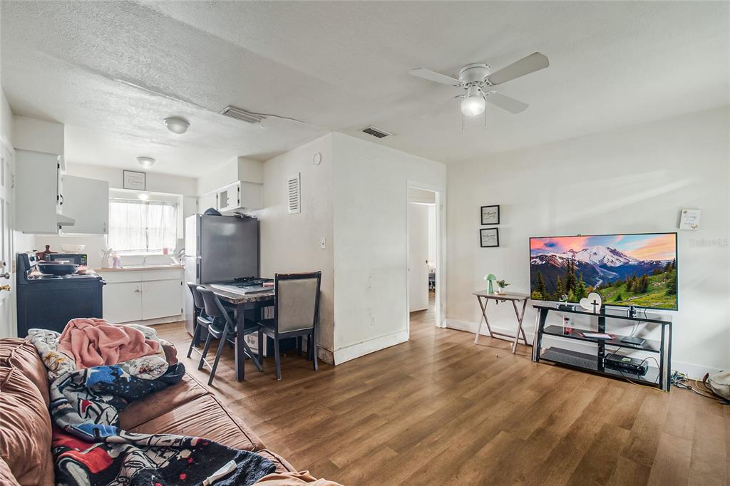 A living room with wood-look flooring, a ceiling fan, and an adjacent kitchen area — 4135 RALEIGH STREET, ORLANDO, FL