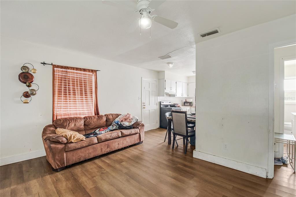 A living room with wood-look flooring, a brown sofa, and an adjacent open kitchen — 4135 RALEIGH STREET, ORLANDO, FL