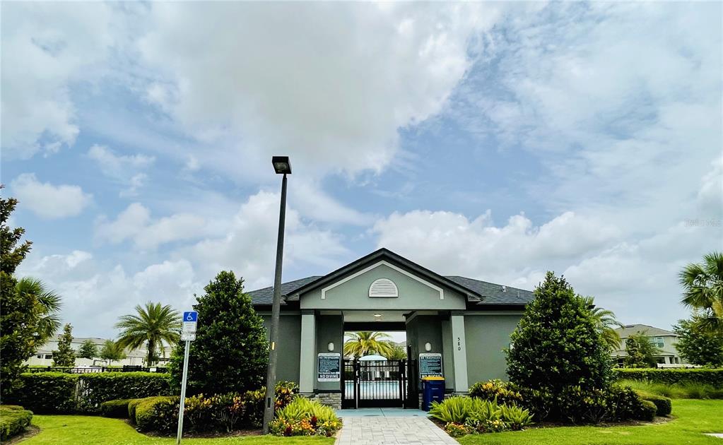 A view of a community pool entrance with a paved walkway and landscaping — 383 LEMONGRASS ROAD, MINNEOLA, FL