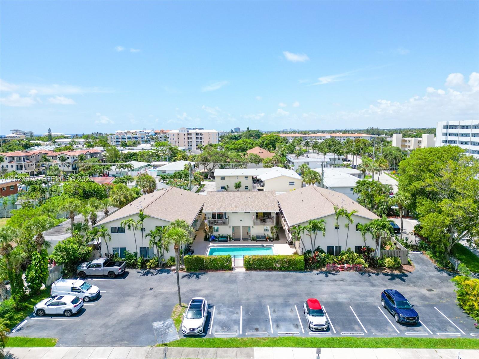 An aerial view shows a two-story apartment complex with a central swimming pool and parking — 1910 NE 5th St # 107, Deerfield Beach FL 33441, DEERFIELD BEACH, FL