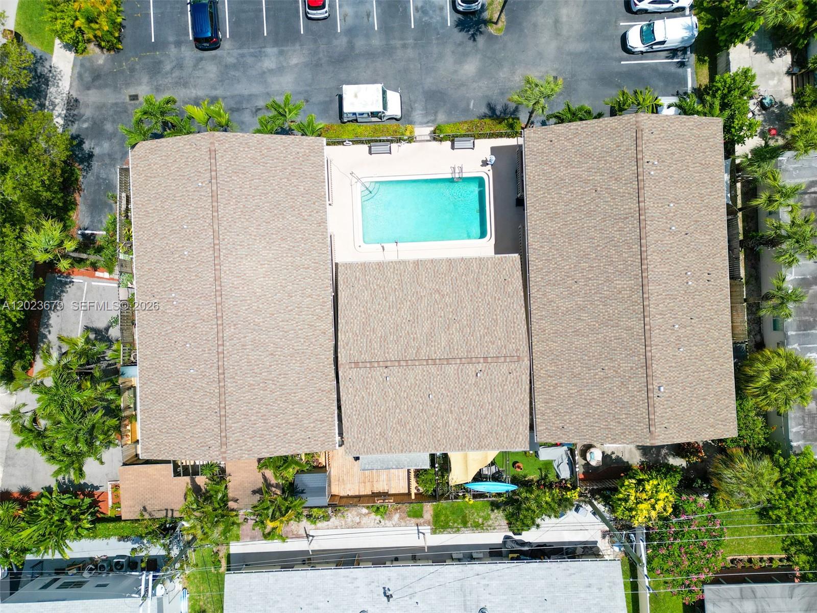 An aerial view shows a building with a central swimming pool and surrounding parking lot — 1910 NE 5th St # 107, Deerfield Beach FL 33441, DEERFIELD BEACH, FL