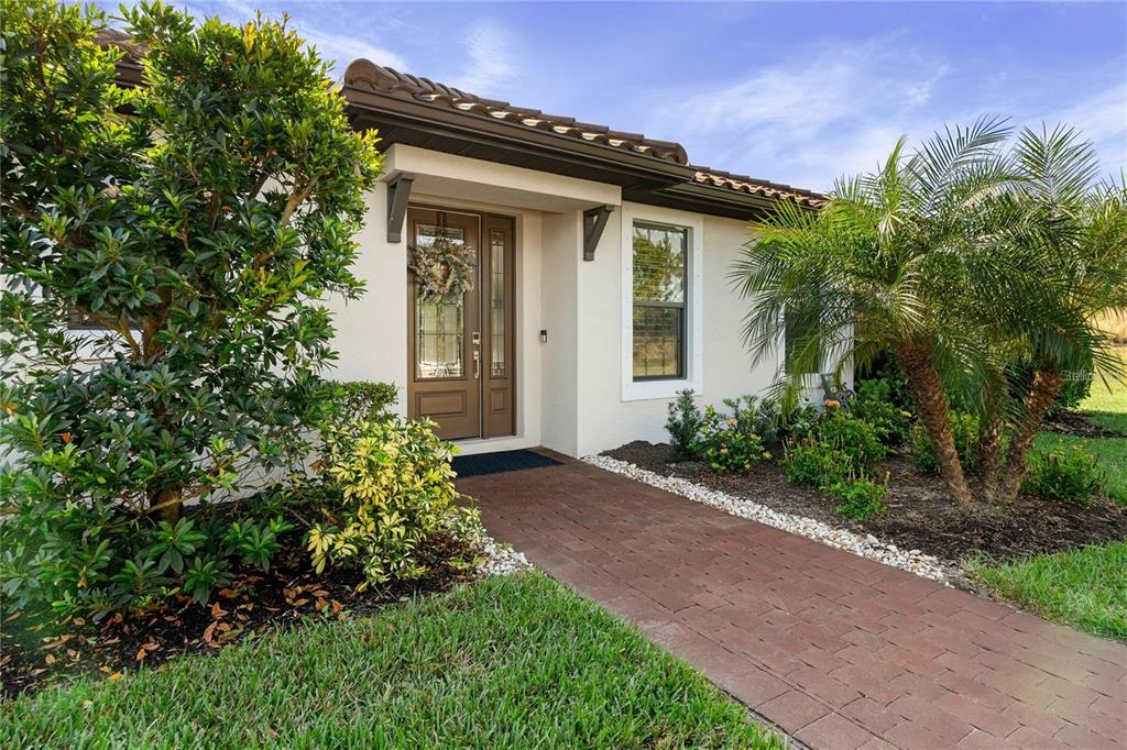 A brick walkway leads to the front entrance of a house with a tiled roof — 15672 SACILE LANE, BRADENTON, FL