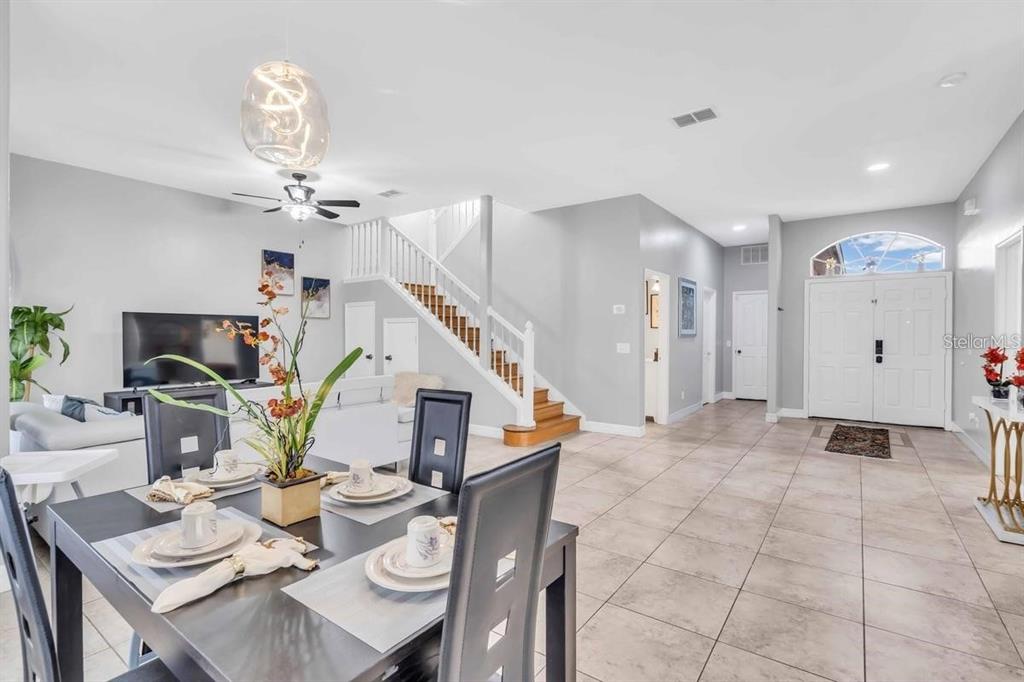A dining area with a dark table overlooks a living room and a wooden staircase — 241 VISTA LOOP, DAVENPORT, FL