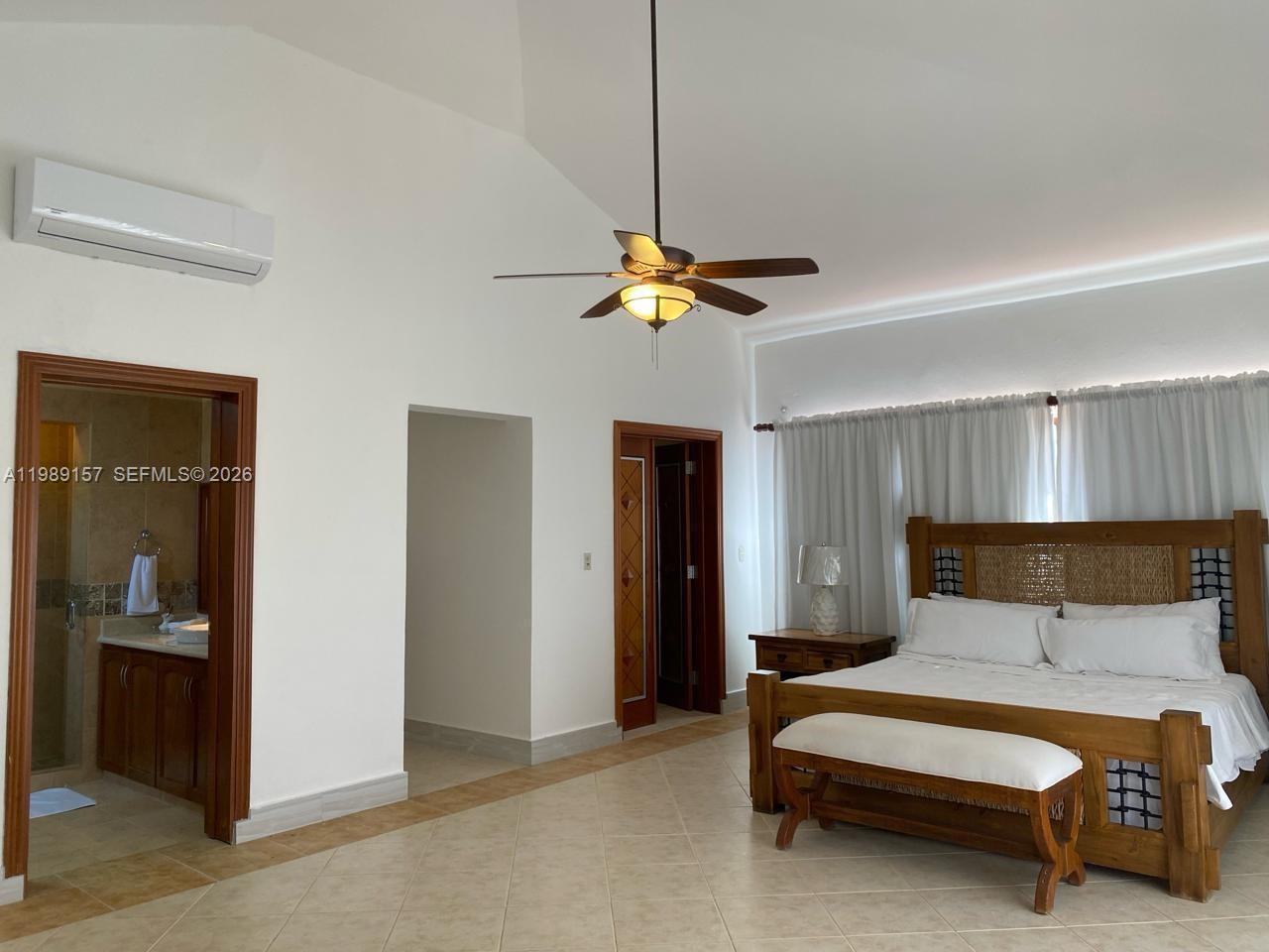 A bedroom features a wooden bed, a ceiling fan, tiled floors, and an attached bathroom — La Canada Town Home 10B (TH10B), FL