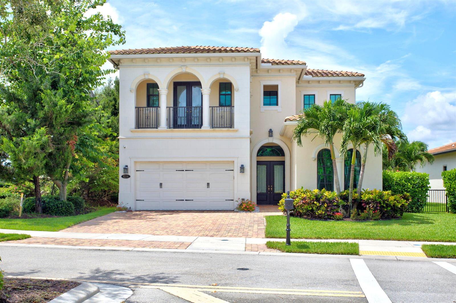 A two-story Mediterranean-style house with a tile roof, arched windows, and a brick driveway — 8236 Grand Prix Lane, Boynton Beach FL 33472, BOYNTON BEACH, FL