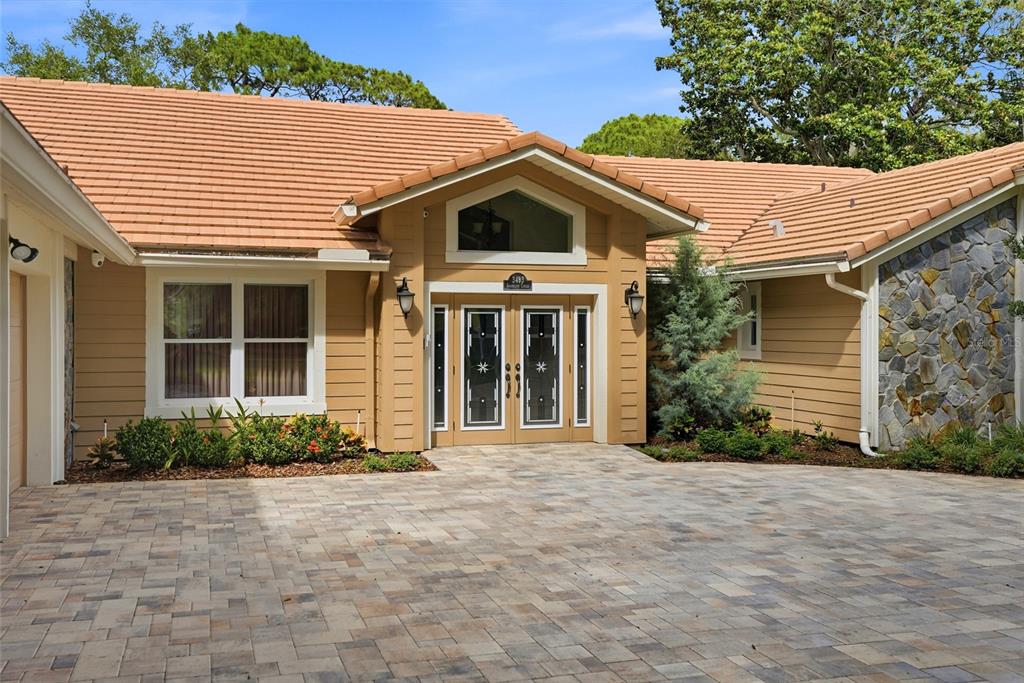 A tan house with a tiled roof, stone accents, and a paved driveway entrance — 3493 SHORELINE CIRCLE, PALM HARBOR, FL