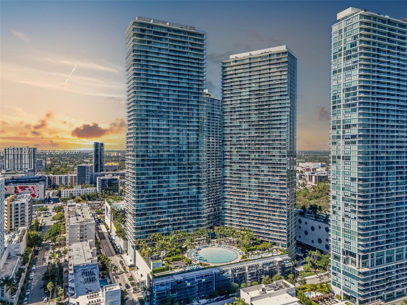 An aerial view shows three tall glass residential towers surrounding a central outdoor swimming pool — 650 NE 32nd St # 2104, Miami FL 33137, MIAMI, FL