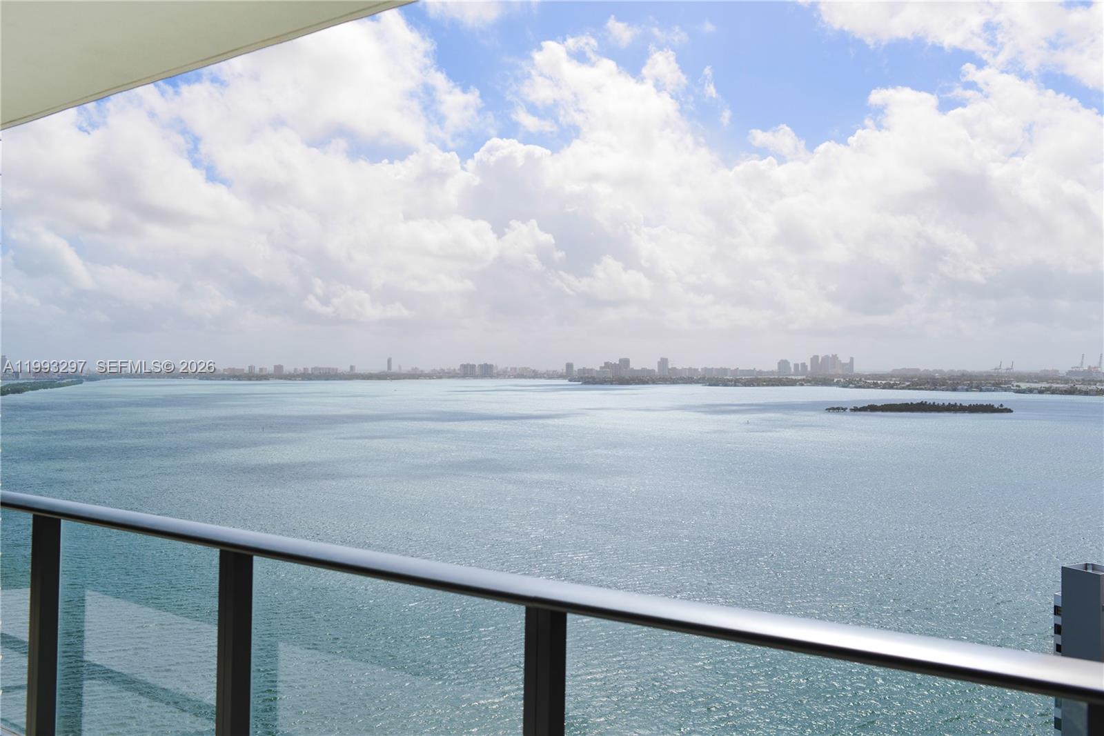 A high-rise balcony overlooks a large body of water with a distant city skyline — 650 NE 32nd St # 2104, Miami FL 33137, MIAMI, FL