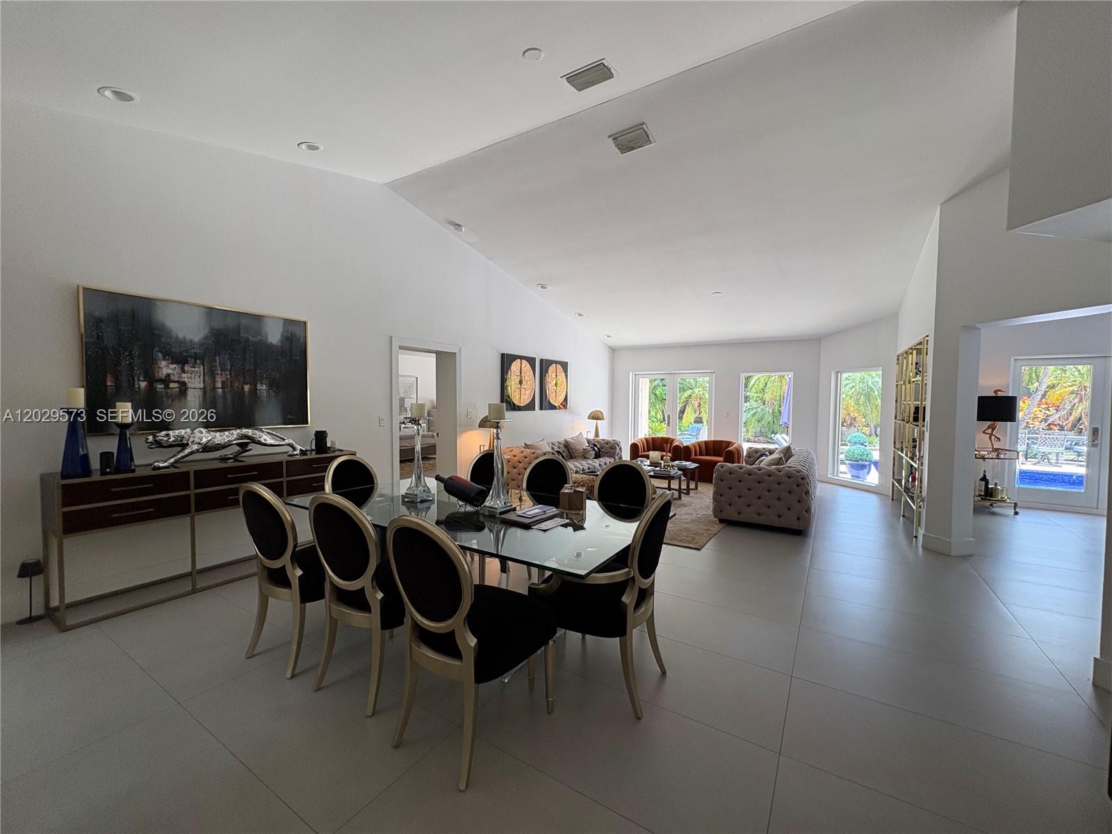 A spacious open-concept living and dining area features white walls, tile flooring, and vaulted ceilings — KEY BISCAYNE, FL