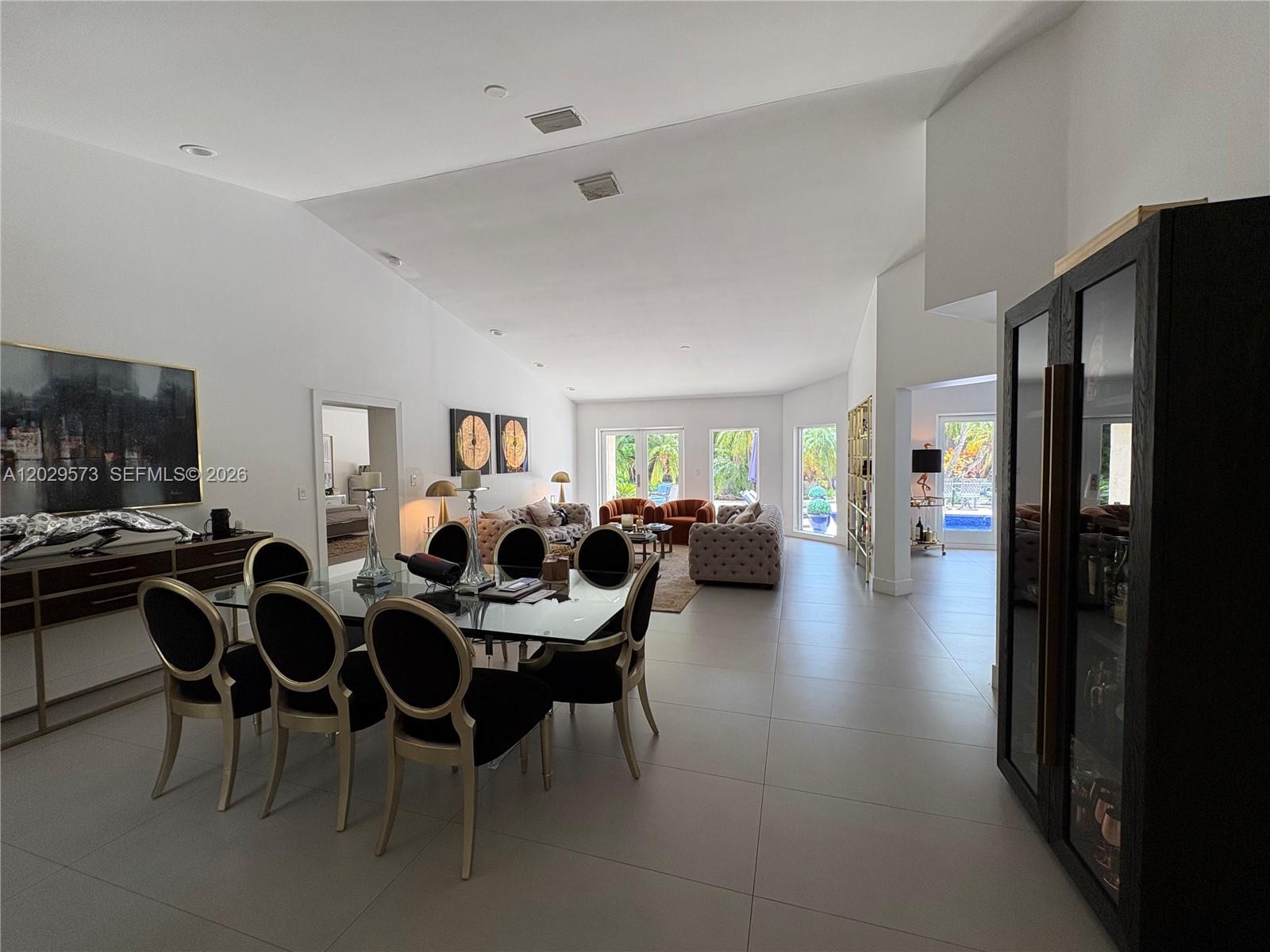 A spacious open-concept living and dining area features white walls, tile flooring, and large windows — KEY BISCAYNE, FL