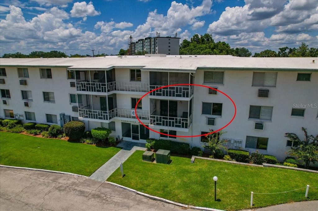An exterior view of a multi-story apartment building with a red circle highlighting a balcony — 1700 6TH ST NW UNIT C24, WINTER HAVEN, FL