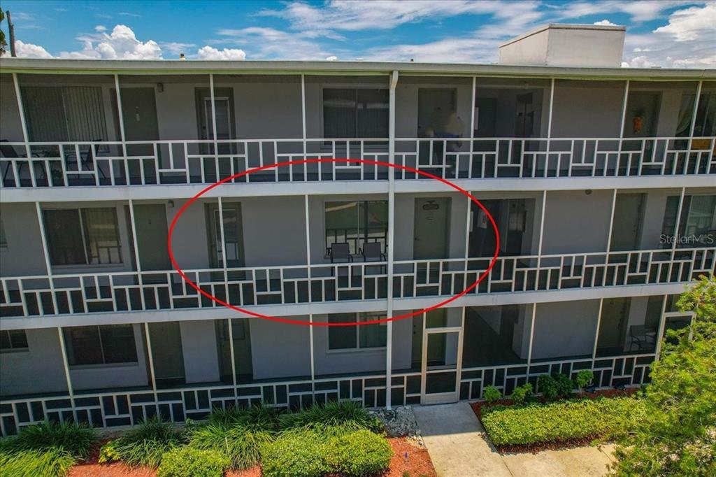 An exterior view of a multi-story apartment building with a screened-in balcony on the second floor — 1700 6TH ST NW UNIT C24, WINTER HAVEN, FL