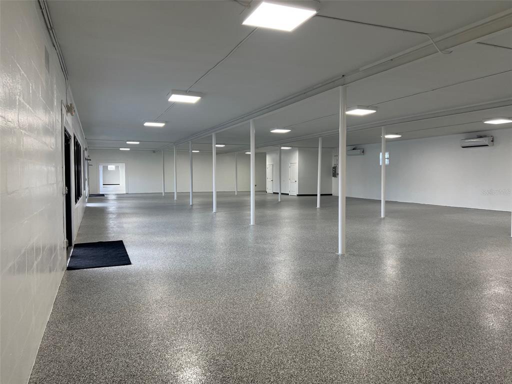 A large, open commercial space features white walls, a speckled epoxy floor, and overhead lighting — 1710 N FORT HARRISON AVENUE, CLEARWATER, FL