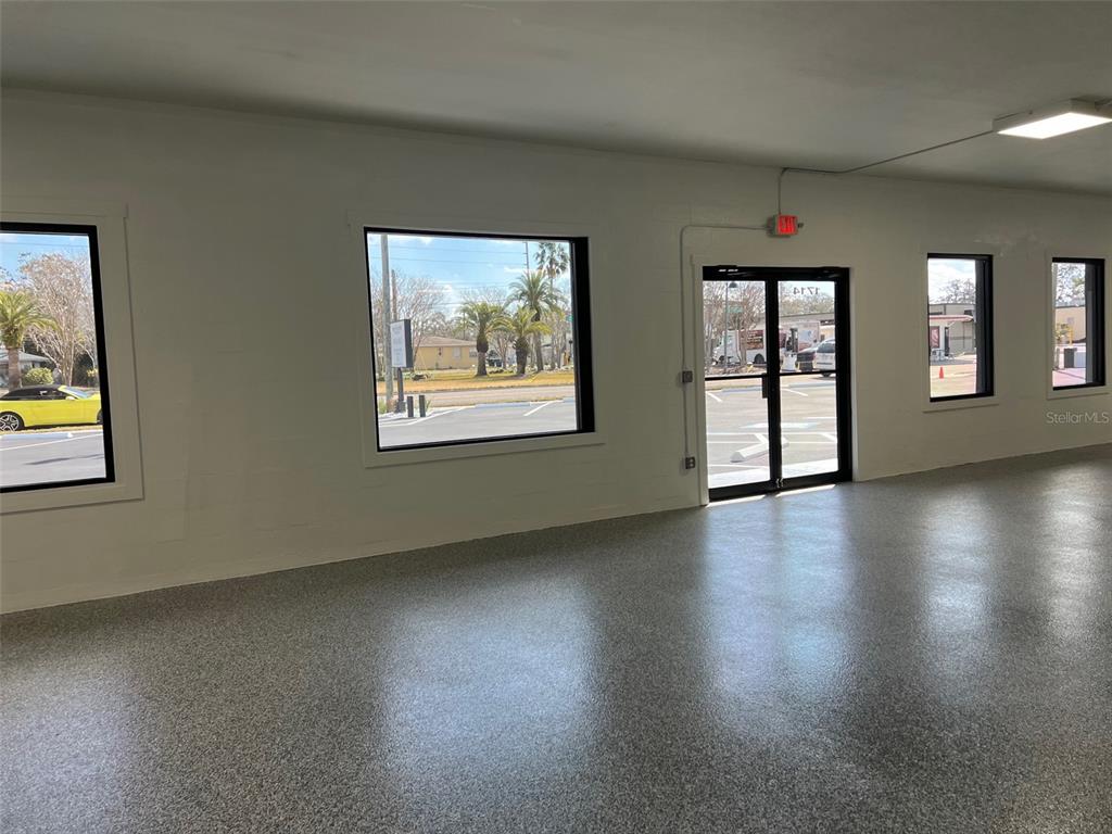 An interior view of a commercial space with white walls, large windows, and speckled flooring — 1710 N FORT HARRISON AVENUE, CLEARWATER, FL