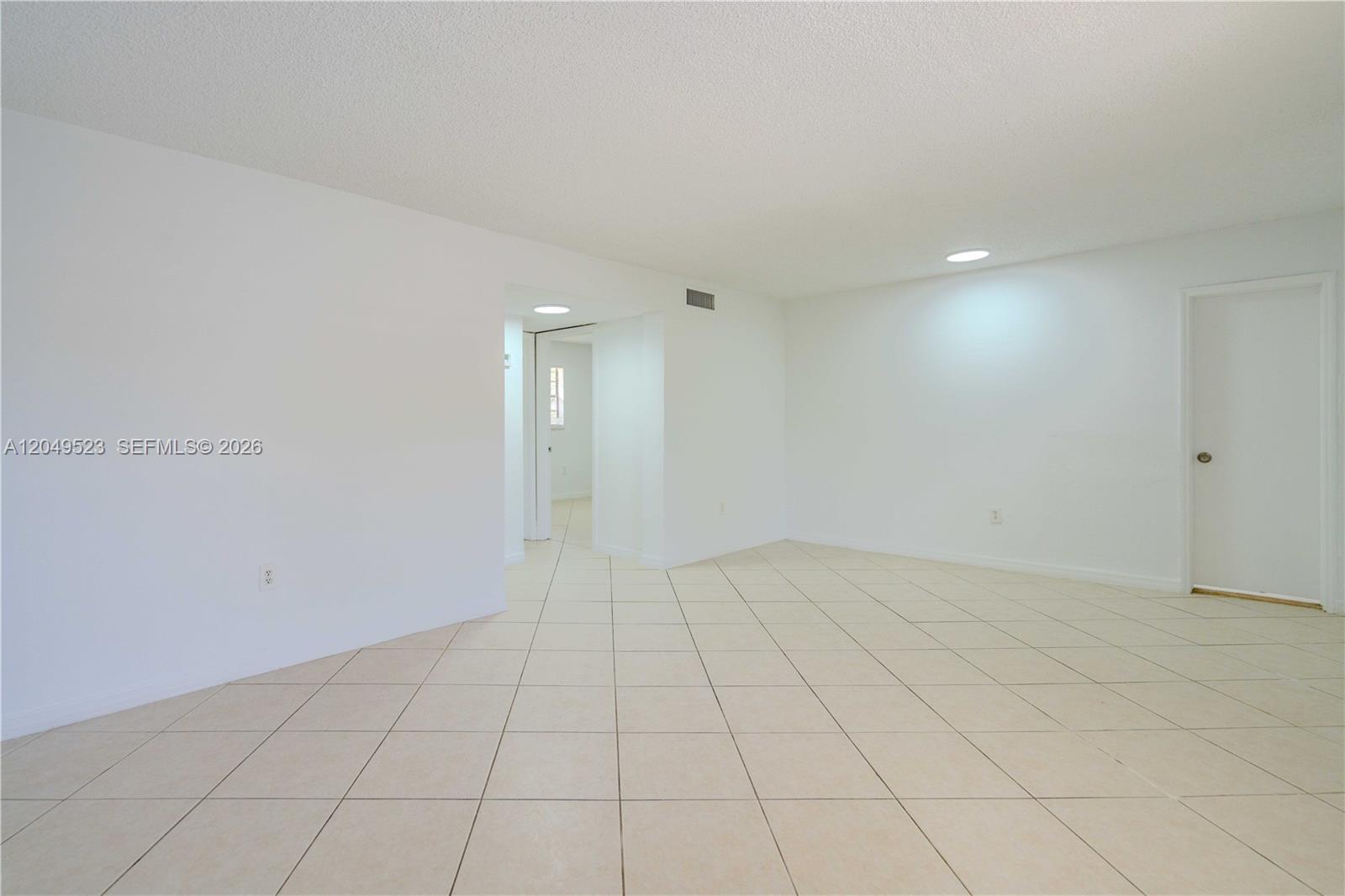 An empty room features white walls, a textured ceiling, and light-colored square floor tiles — 3265 Virginia St # 15, Miami FL 33133, MIAMI, FL