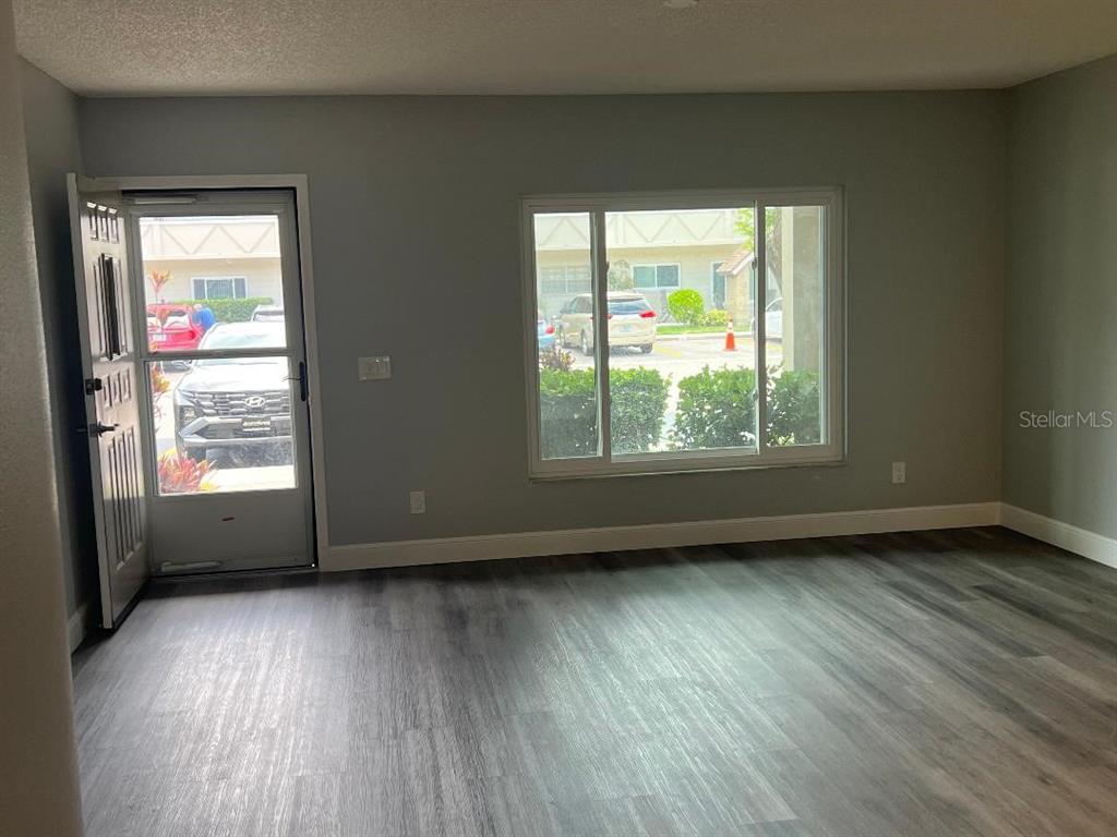 A room with gray walls, wood-look flooring, a glass-paneled door, and a large window — 2294 BELGIAN LANE UNIT 14, CLEARWATER, FL