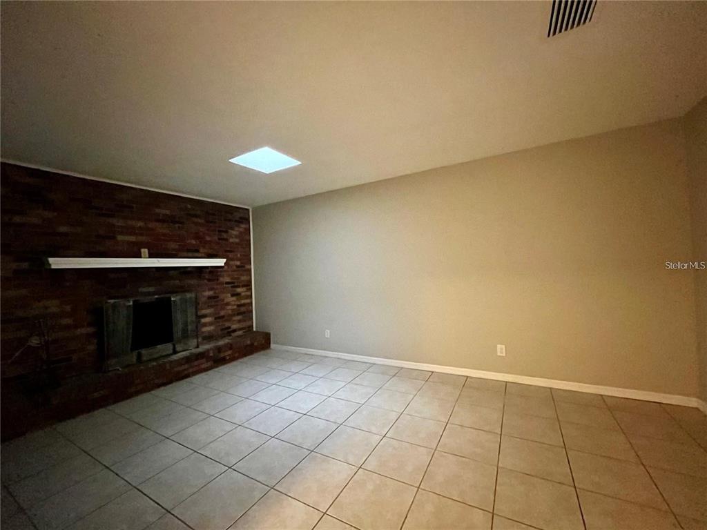 A living room features a brick fireplace, tile flooring, and a skylight — 3029 SLEEPY HILL ROAD, LAKELAND, FL