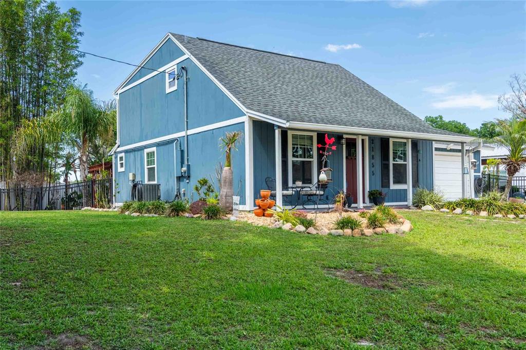 A blue two-story house with a front porch and a landscaped rock garden — 21855 OCEAN PINES DRIVE, LAND O LAKES, FL