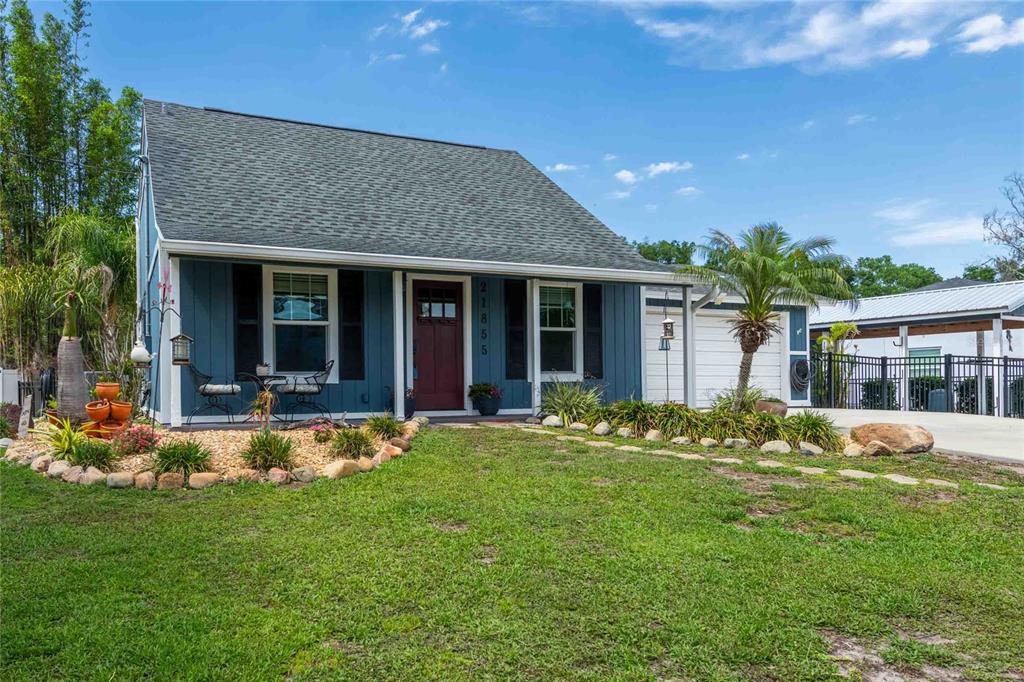 A blue house with a dark roof, a red front door, and a grassy front yard — 21855 OCEAN PINES DRIVE, LAND O LAKES, FL