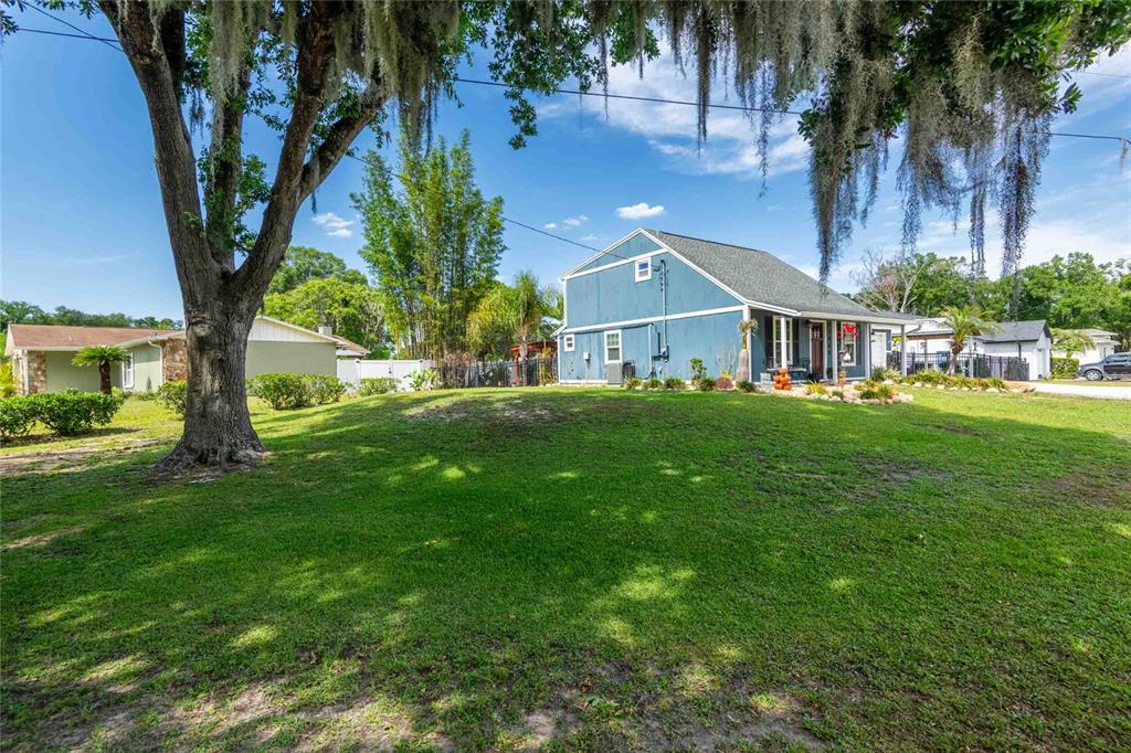 A blue two-story house sits on a grassy lot with a large tree in front — 21855 OCEAN PINES DRIVE, LAND O LAKES, FL