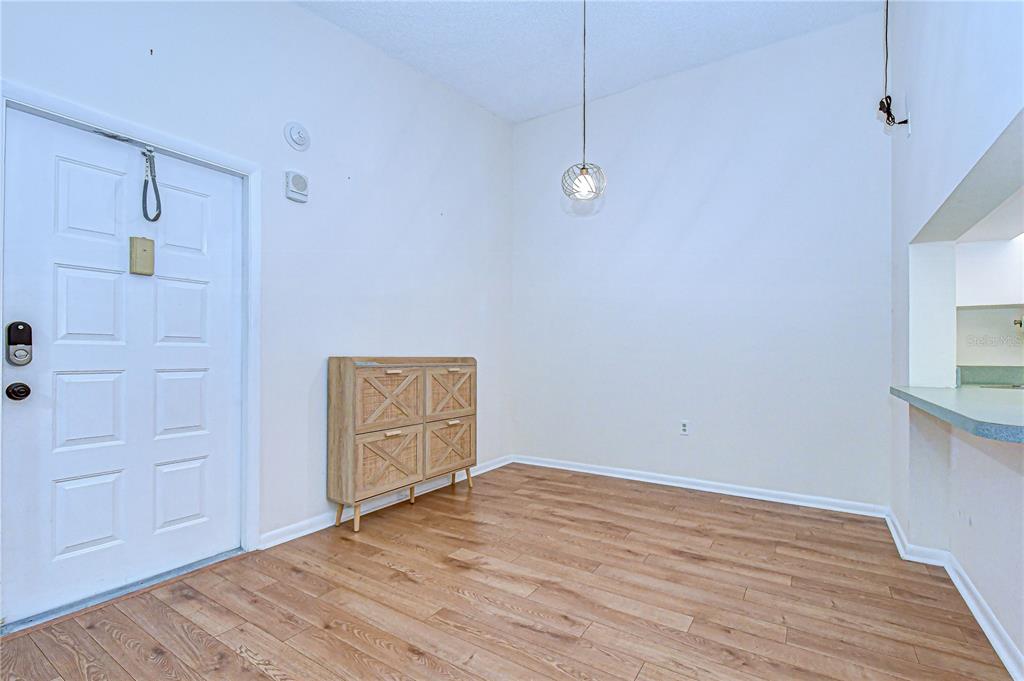 A dining area features wood-look flooring, a light wood cabinet, and a modern pendant light — 3161 LAKE PINE WAY S UNIT F3, TARPON SPRINGS, FL
