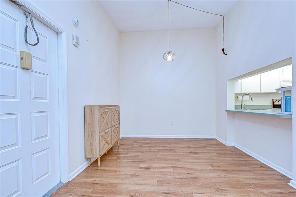 An empty dining area features wood-look flooring, a light wood cabinet, and a hanging pendant light — 3161 LAKE PINE WAY S UNIT F3, TARPON SPRINGS, FL