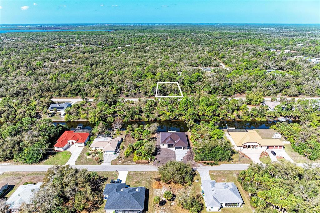 An aerial view shows a vacant, rectangular lot outlined in white above a canal — 3107 COMO STREET, PORT CHARLOTTE, FL