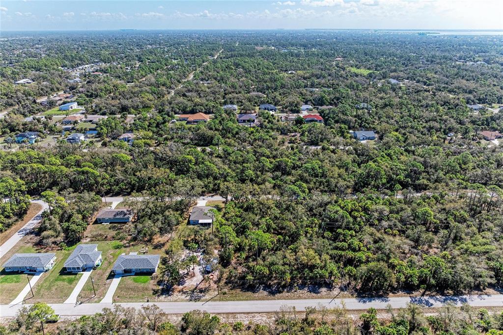 An aerial view shows several houses surrounded by dense trees and a paved road — 3107 COMO STREET, PORT CHARLOTTE, FL