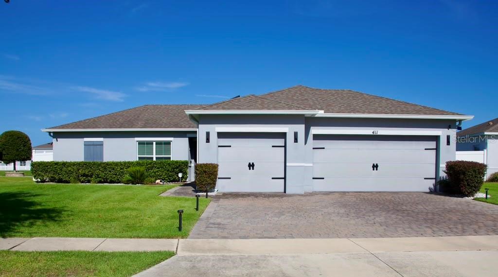 A single-story house with a gray exterior, a three-car garage, and a paved driveway — 411 BLUE LAKE CIRCLE, KISSIMMEE, FL