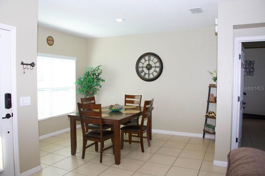 A dining area features a wooden table with four chairs, tile flooring, and a wall clock — 411 BLUE LAKE CIRCLE, KISSIMMEE, FL