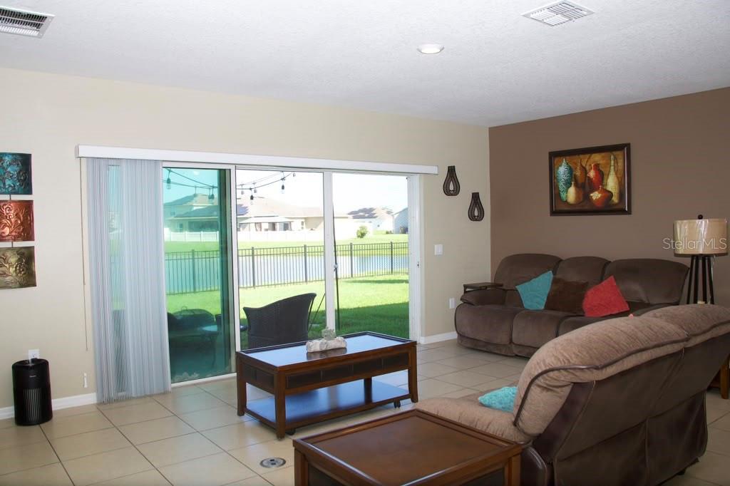 A living room features tile floors, a brown sofa, a coffee table, and sliding glass doors — 411 BLUE LAKE CIRCLE, KISSIMMEE, FL