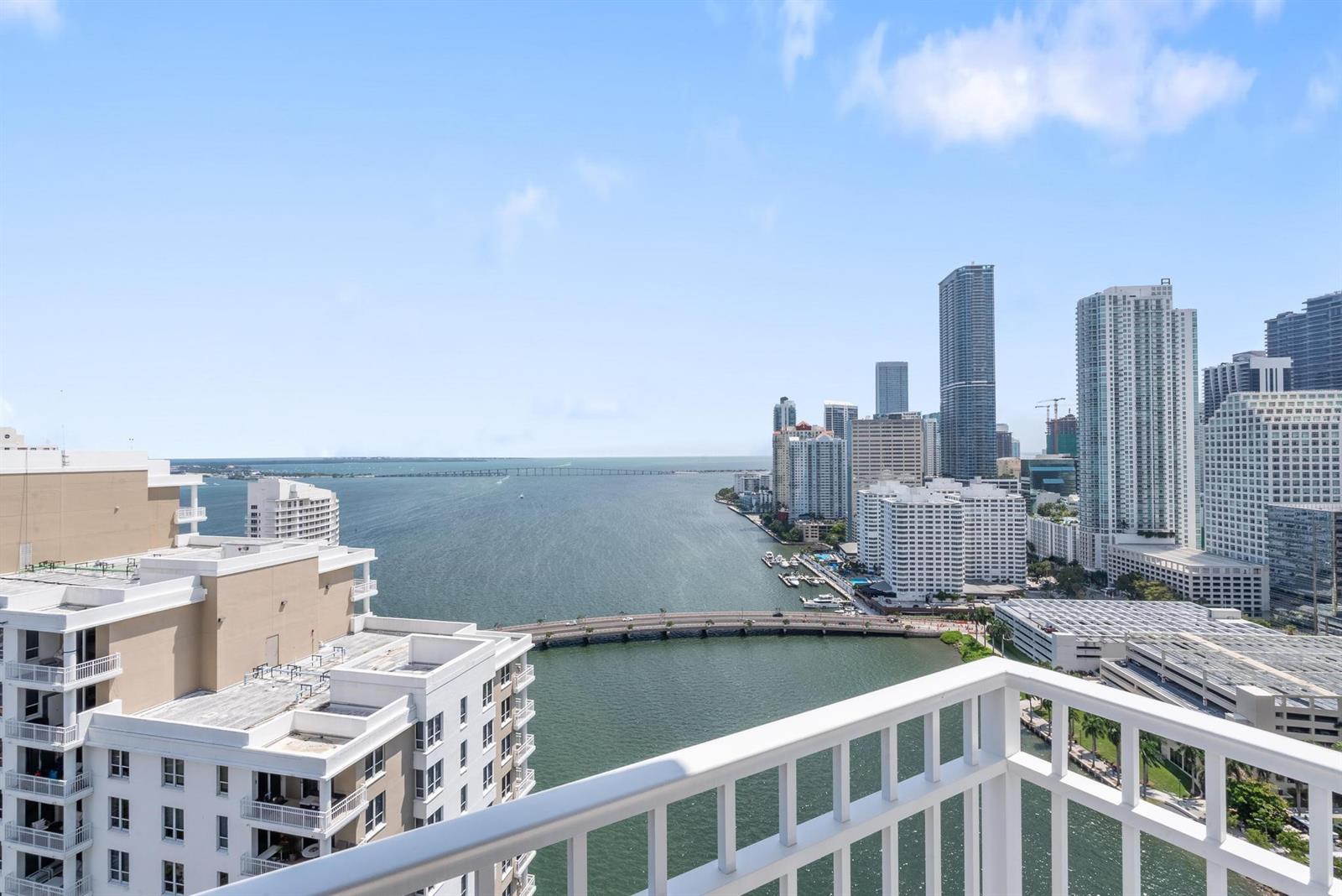 A high-angle view from a balcony overlooking a bay, a bridge, and a city skyline — 801 Brickell Key Boulevard # 2903, Miami FL 33131, MIAMI, FL