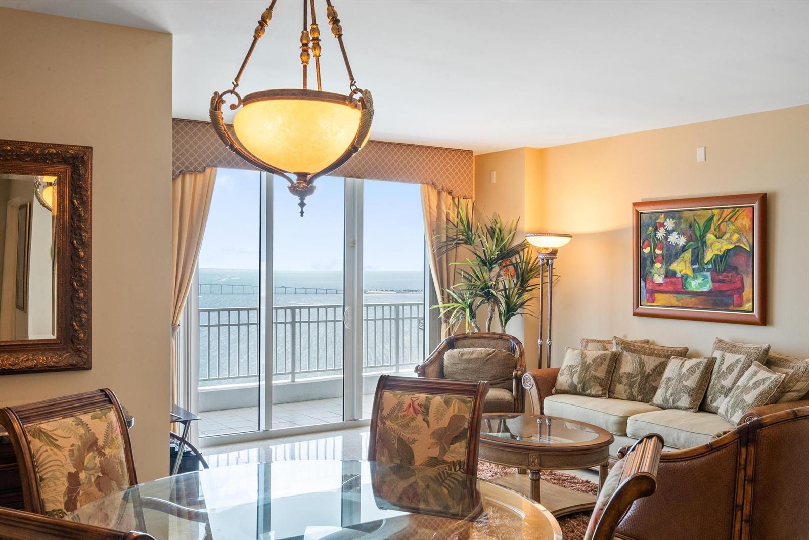 A dining and living area features a glass table, tropical-patterned furniture, and a balcony view — 801 Brickell Key Boulevard # 2903, Miami FL 33131, MIAMI, FL