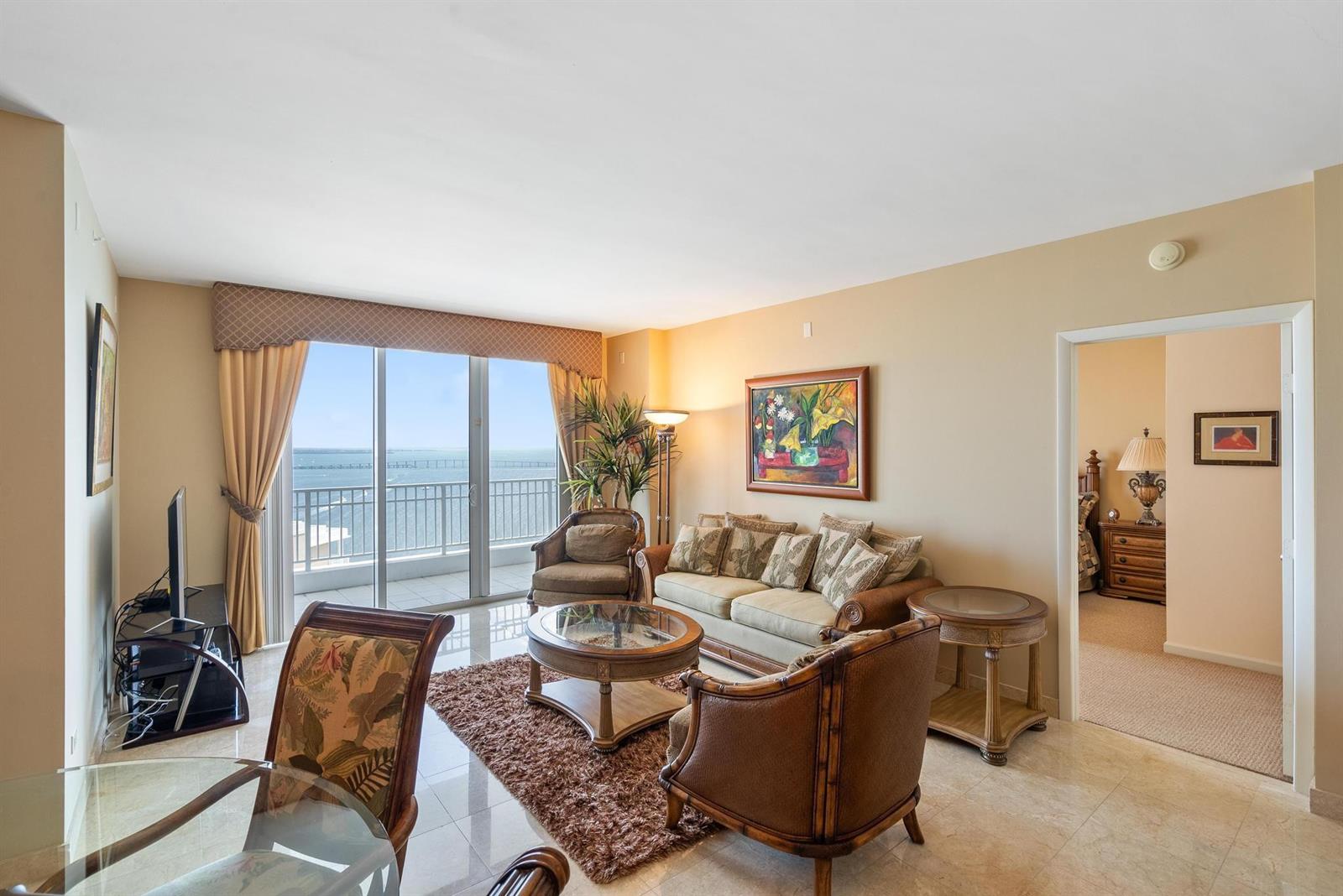 A living room with tile floors, a sofa, armchairs, and a balcony overlooking the ocean — 801 Brickell Key Boulevard # 2903, Miami FL 33131, MIAMI, FL