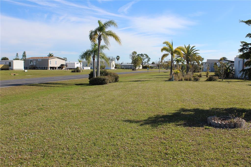 A grassy vacant lot with palm trees and mobile homes in a residential neighborhood — 7392 HESTON STREET, PORT CHARLOTTE, FL
